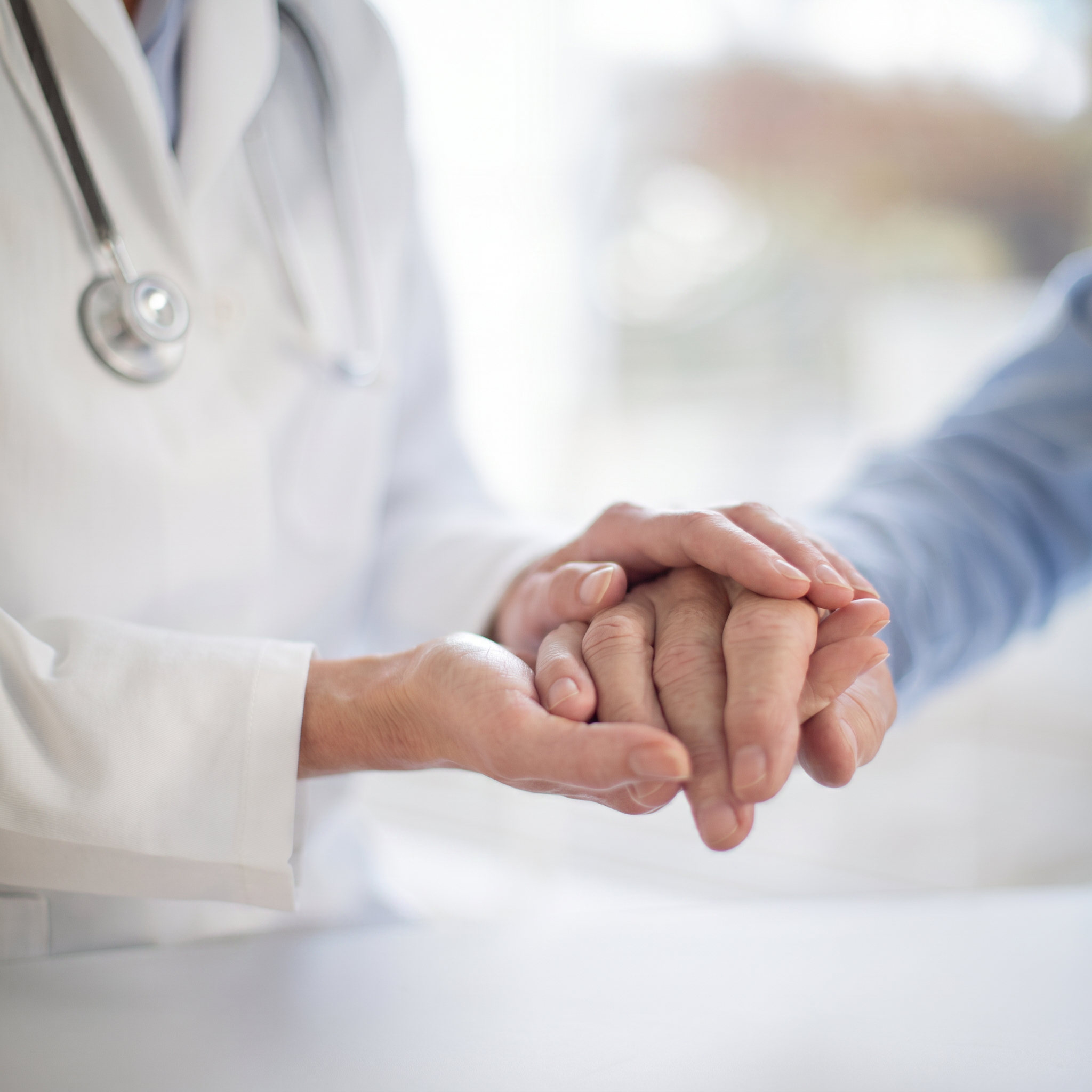 Physician holding a patient's hand during a consultation