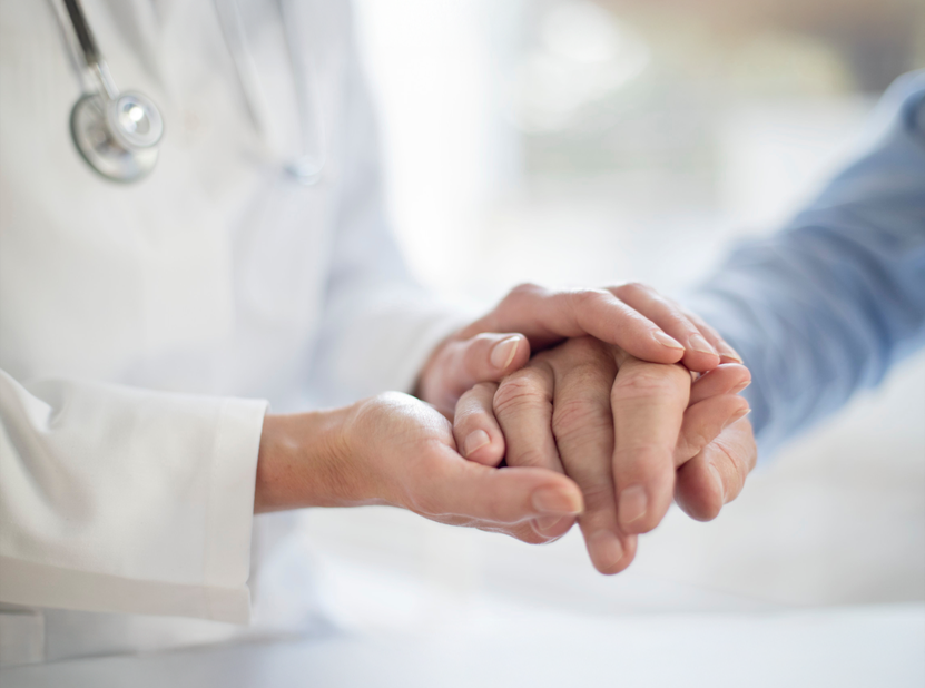 Physician holding a patient's hand during a consultation